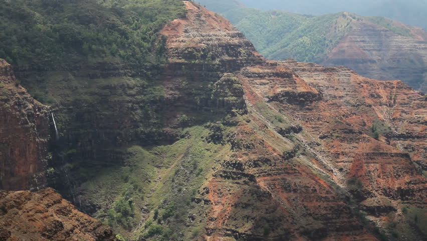 elevated view of a tropical canyon with reddish soil and green growth