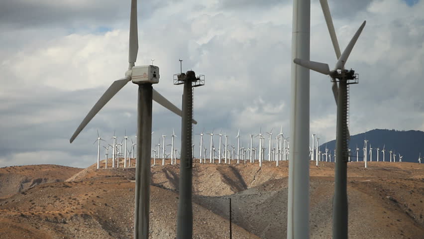At sunset multiple desert wind turbines with blades turning