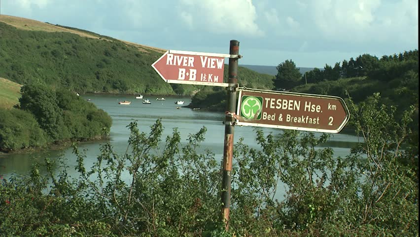 Irish road sign with 2 b & b's listed, with small fjord in back ground in late afternoon light