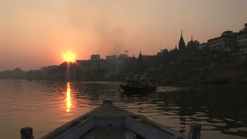 setting sun over Ganges and pilgrim boat comes through frame.Circa November, 2008, Veranasi, India