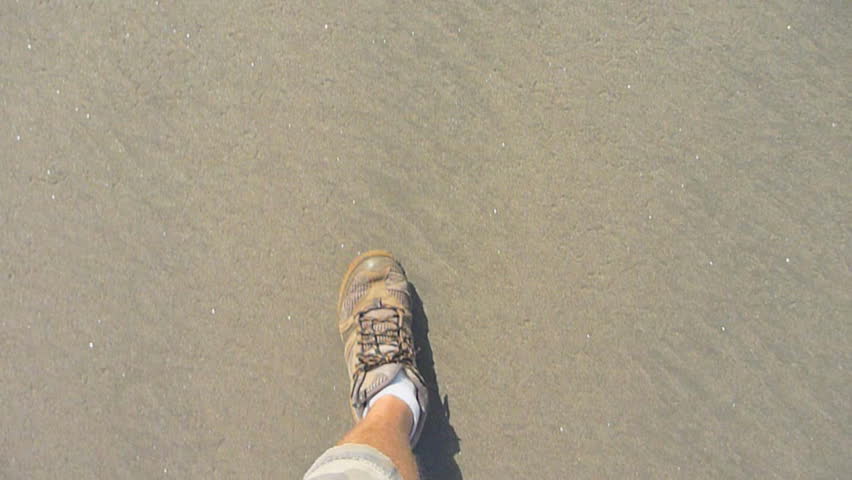 Man hikes on sandy beach point of view.