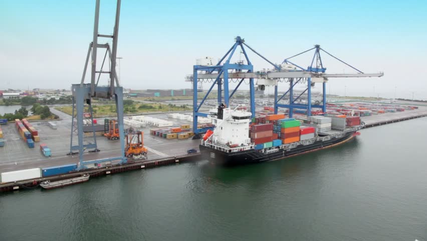 Machines ride and shipment of barge with containers by large crane in seaport at day