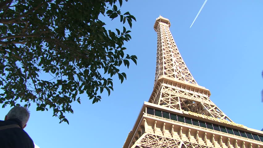 LAS VEGAS - CIRCA MARCH 2010: Las Vegas Paris Eiffel Tower scenic during the day with people walking around and airplane flying showing contrails.