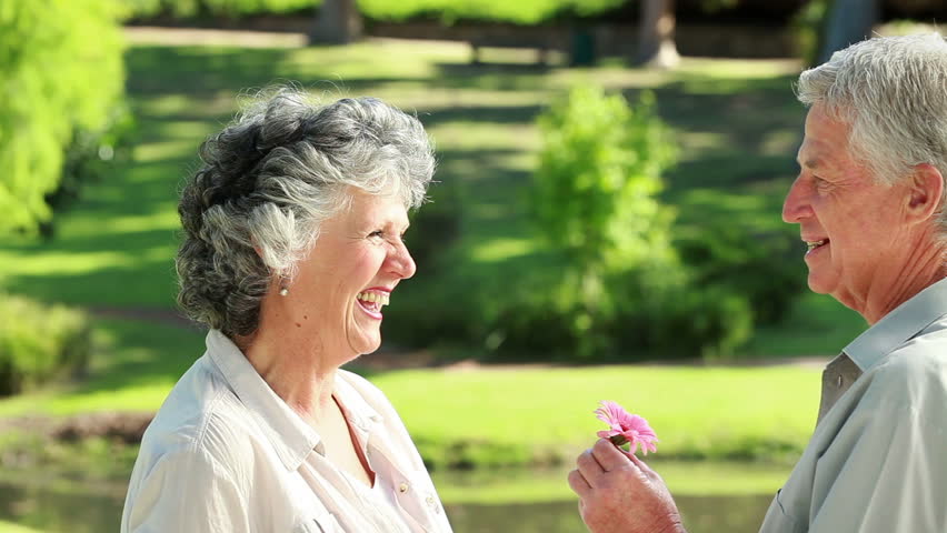 Smiling mature man giving a flower to his wife in the countryside