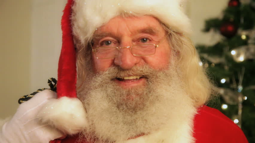 Santa Clause smiling in front of a Christmas tree