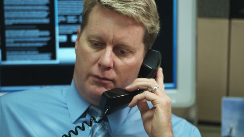 pan shot of man talking seriously on telephone (no audio)