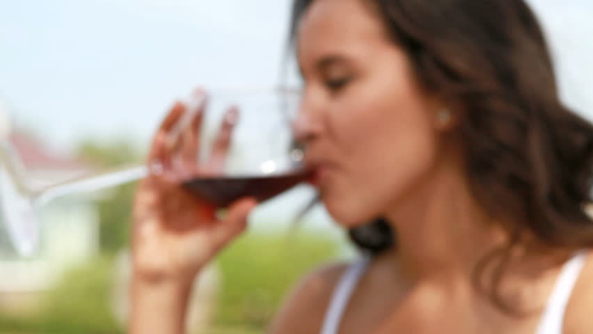 Girl drinking red wine as aperitif before main course, selective focus