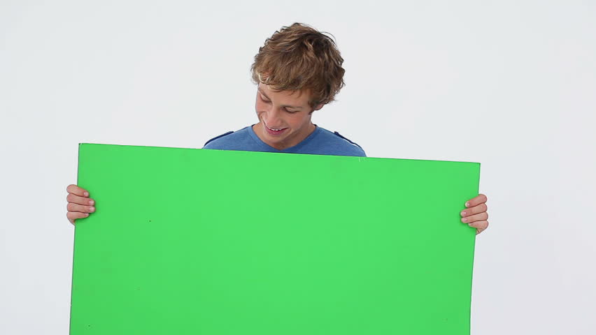 Smiling brunette man holding a blank poster against a white background