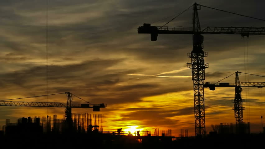 Construction cranes fading from sunset to dusk