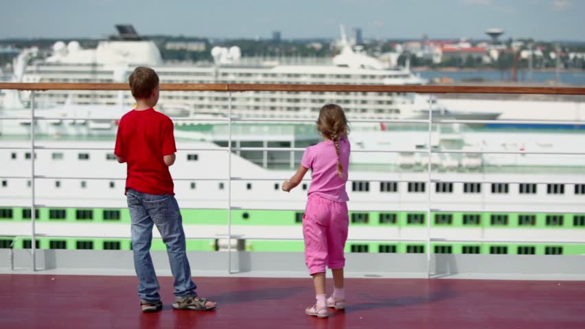 Two kids boy with girl throw pieces of bread to feed gulls in port at sunny day