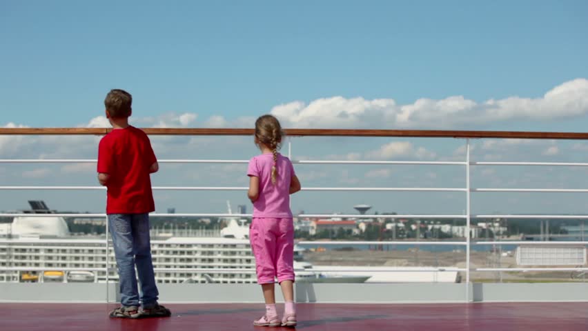 Two kids brother with sister throw pieces of bread to feed gulls in port at sunny day
