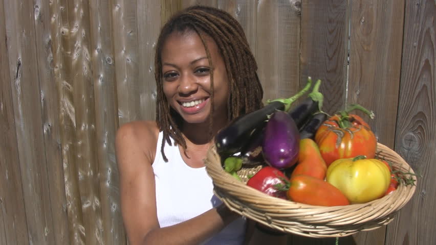 A pretty girl holds a basket of home-grown vegetables.