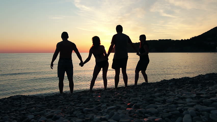 Group of people dancing on the beach at sunset, group of happy young people dancing at the beach on beautiful summer sunset