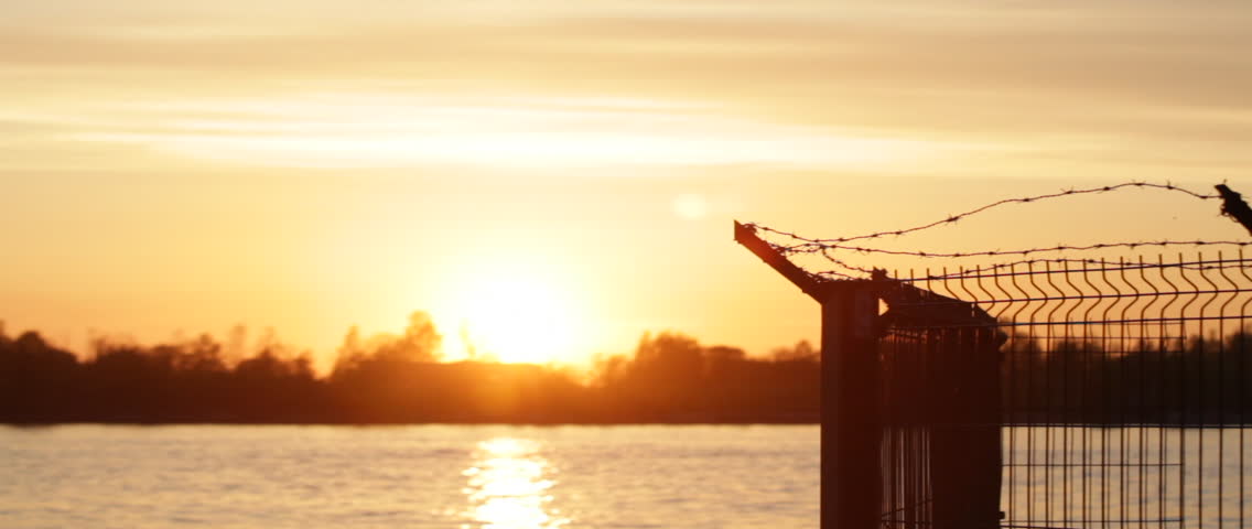 Prison barbed wire fence at sunset