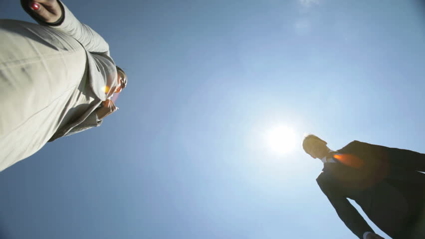 Business partners meeting under clear blue sky and shaking hands