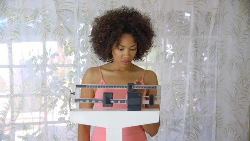 Young woman recording weight loss on scale
