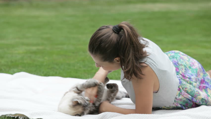 young woman playing with cat on nature
