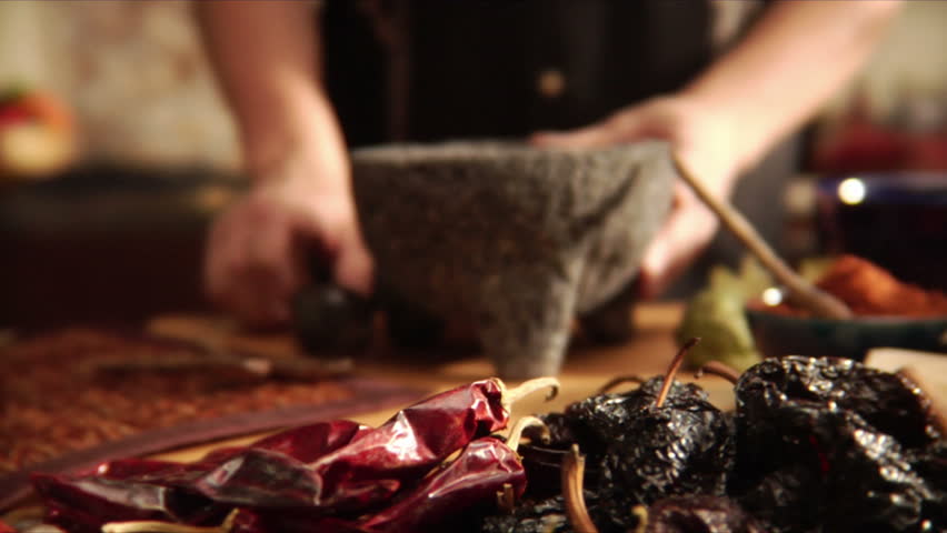 Chef crushing mexican spices with mortar and pestle