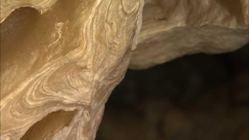 Pan across growth rings in broken stalactite in cave