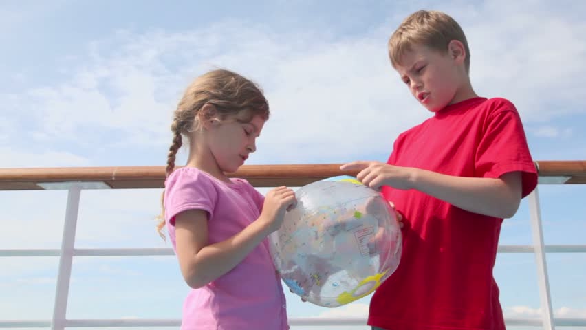 Two kids boy with little girl stand near railing and hold inflated ball with earth texture