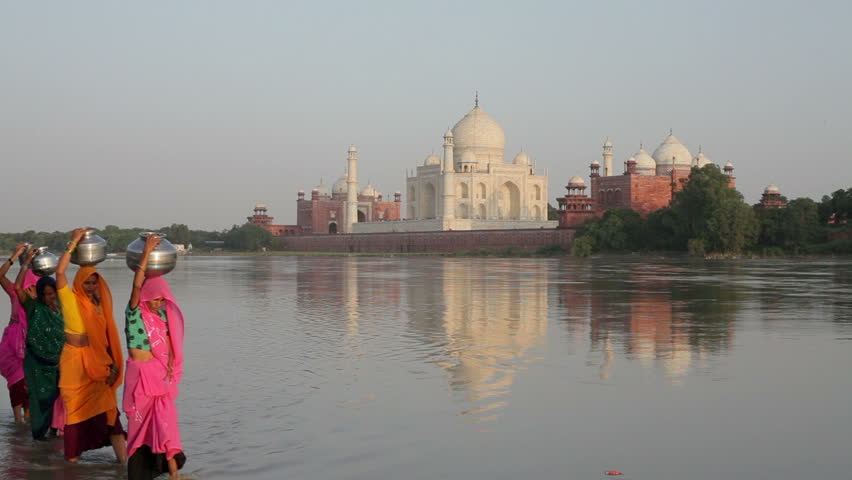 Taj Mahal in the background with women in colorful Saris collecting water