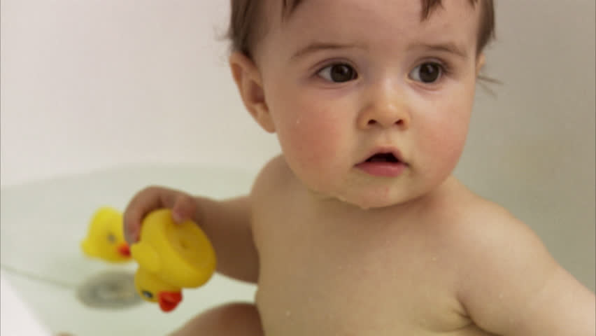 Child sitting in a bathtub chewing a rubber duck