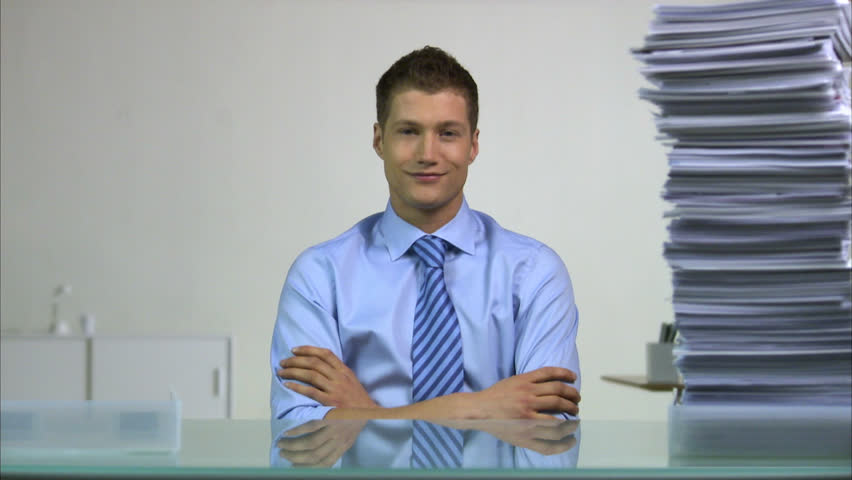 Man sitting behind a desk, using his finger to decrease the pile of paper beside him