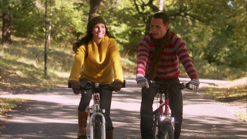 A woman and a man riding a bike an autumn day