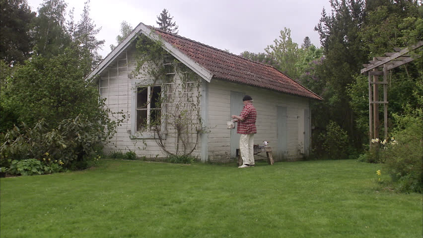Elderly man painting his summer cottage