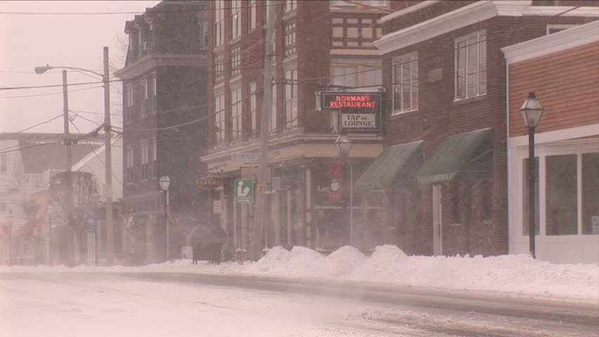 NEW ENGLAND - CIRCA JANUARY 2006: Car passing small retail storefronts in snowstorm