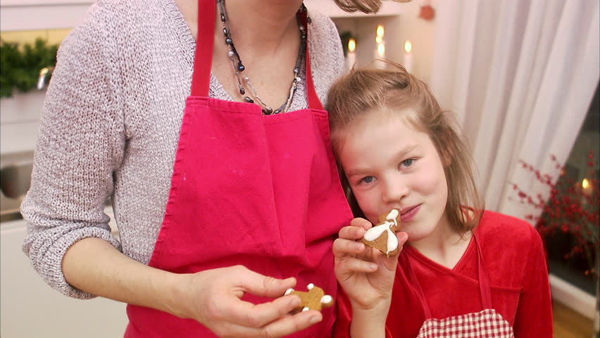 Mother and daughter eating gingerbread biscuits