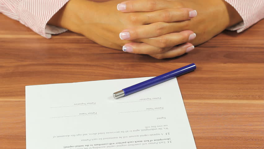 Woman signing a contract - Unrecognizeable person signs a legal document using a fountain pen