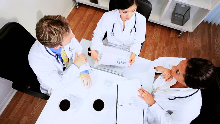 Young multi ethnic medical doctors concluding meeting in the boardroom of a modern hospital building