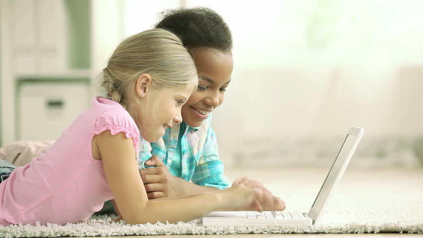 Two schoolgirls using laptop to communicate with their friends