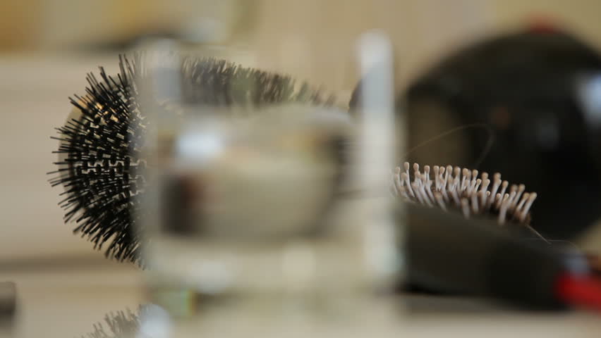 Hairbrushes and a glass of water on a table.