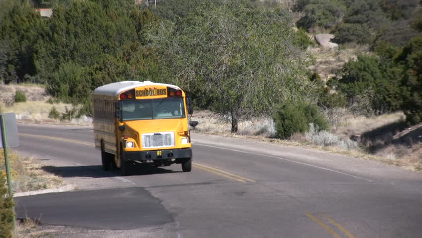 HD shot of a school bus coming down the road towards and past the camera position