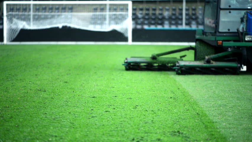 Cutting grass in a football stadium with mowing equipment