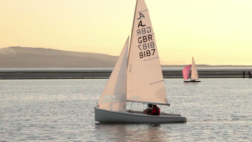 WEST KIRBY, WIRRAL/ENGLAND - AUGUST 9: Camera pans with sail boat on peaceful lake at sunset on August 9, 2012 in West Kirby. The Marine Lake is a man made coastal lake fed by the sea at high tide.  