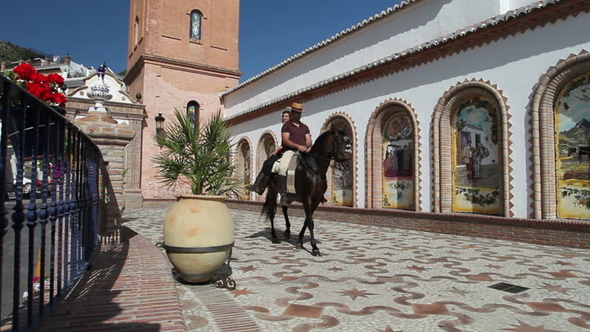 Man and woman riding a horse through a village in Andalusia, Spain