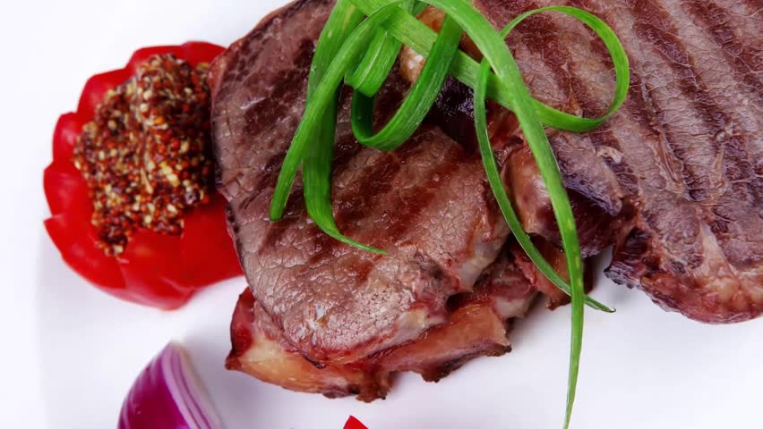 grilled meat beef steaks strips on white plate with sweet pea and tomatoes
