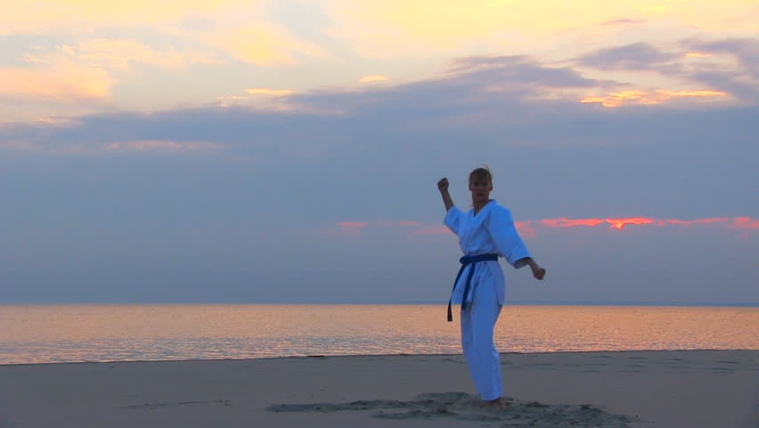young woman training karate on sunset beach