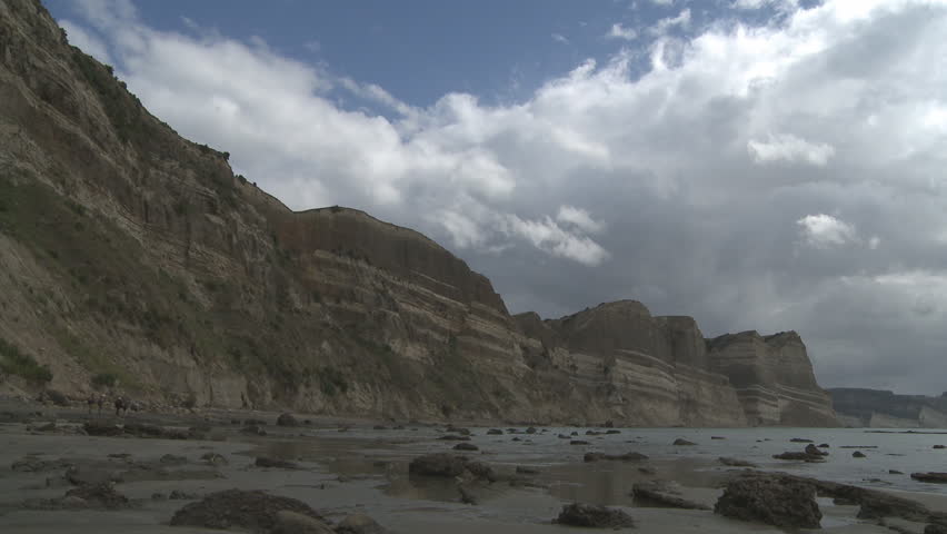 large, eroding cliffs show sedimentary layers from down over the ages.Timelapse of approaching storm.