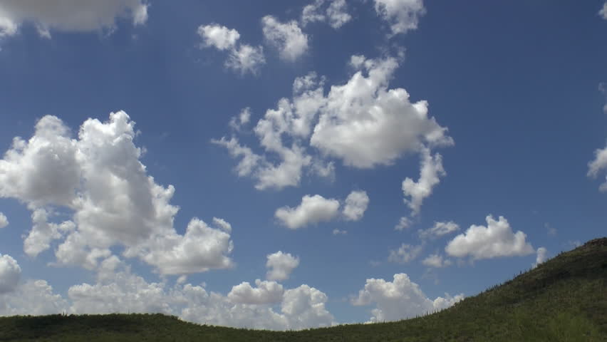 Time Lapse, Light, fluffy, billowy clouds soar across blue sky over Arizona desert landscape. 1080p