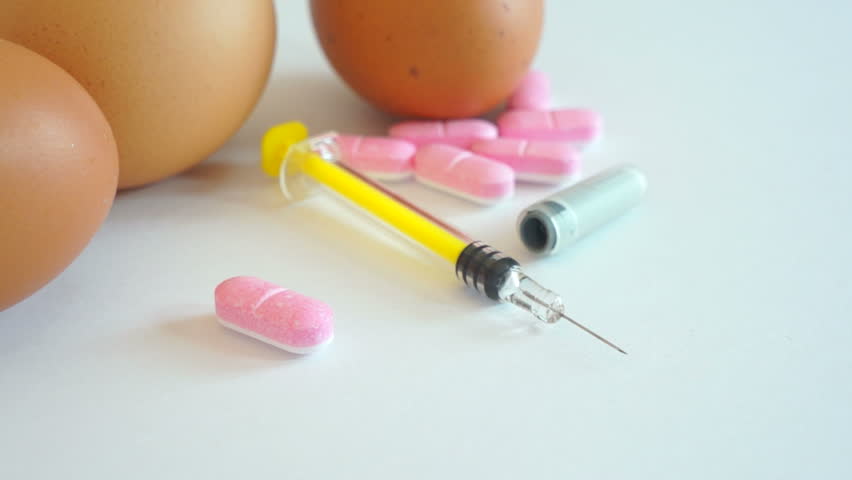 Sliding dolly shot of a medical syringe and drug pills together with chicken eggs.