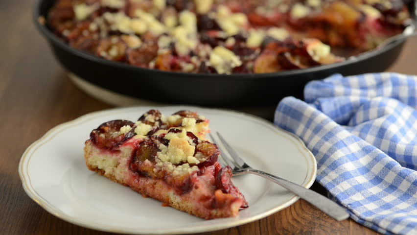 putting on a plate with plum cake of crumpet some whipped cream. Baking sheet with cake in background.
