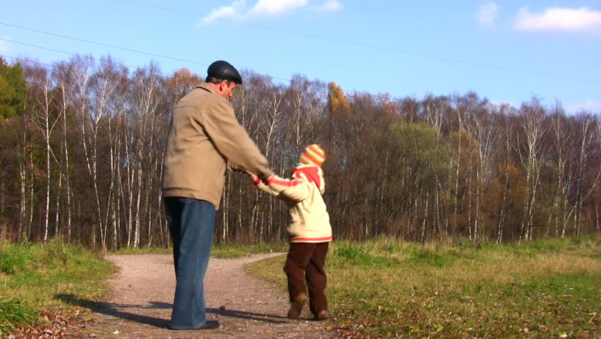 grandfather rotate boy in autumn park 