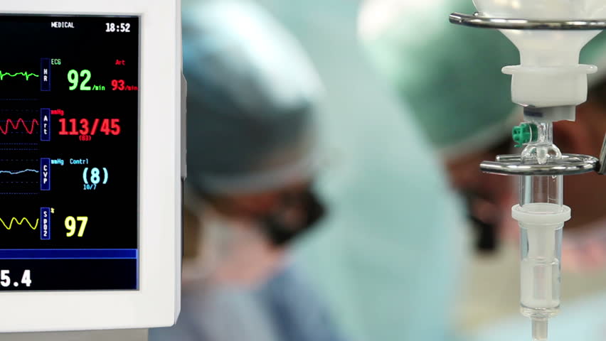 intravenous drip with monitor in operation room with surgeons on background