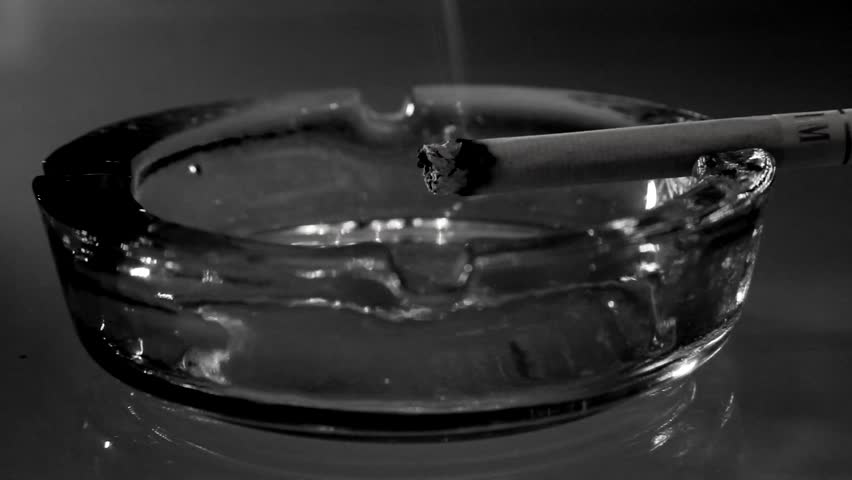 A burning cigarette in an ashtray -black and white