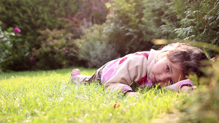 A little girl is rolling in the grass, dolly