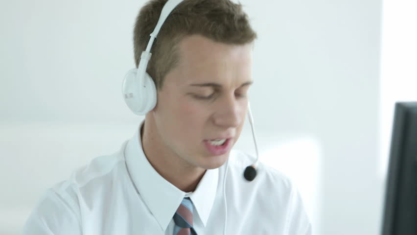 Young helpdesk operator communicating with a client via headset